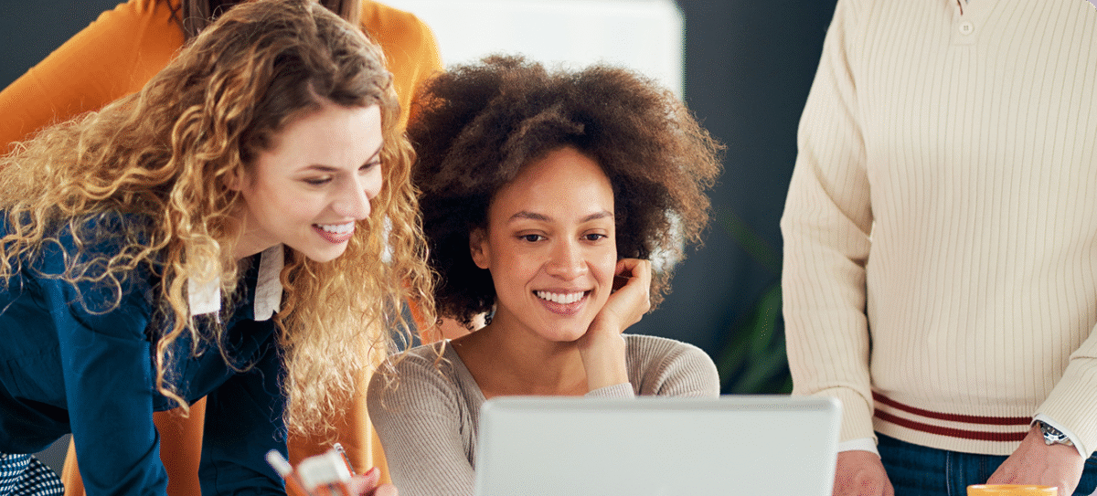 Meerdere collega’s kijken glimlachend naar een laptop en werken samen in een informele kantooromgeving.